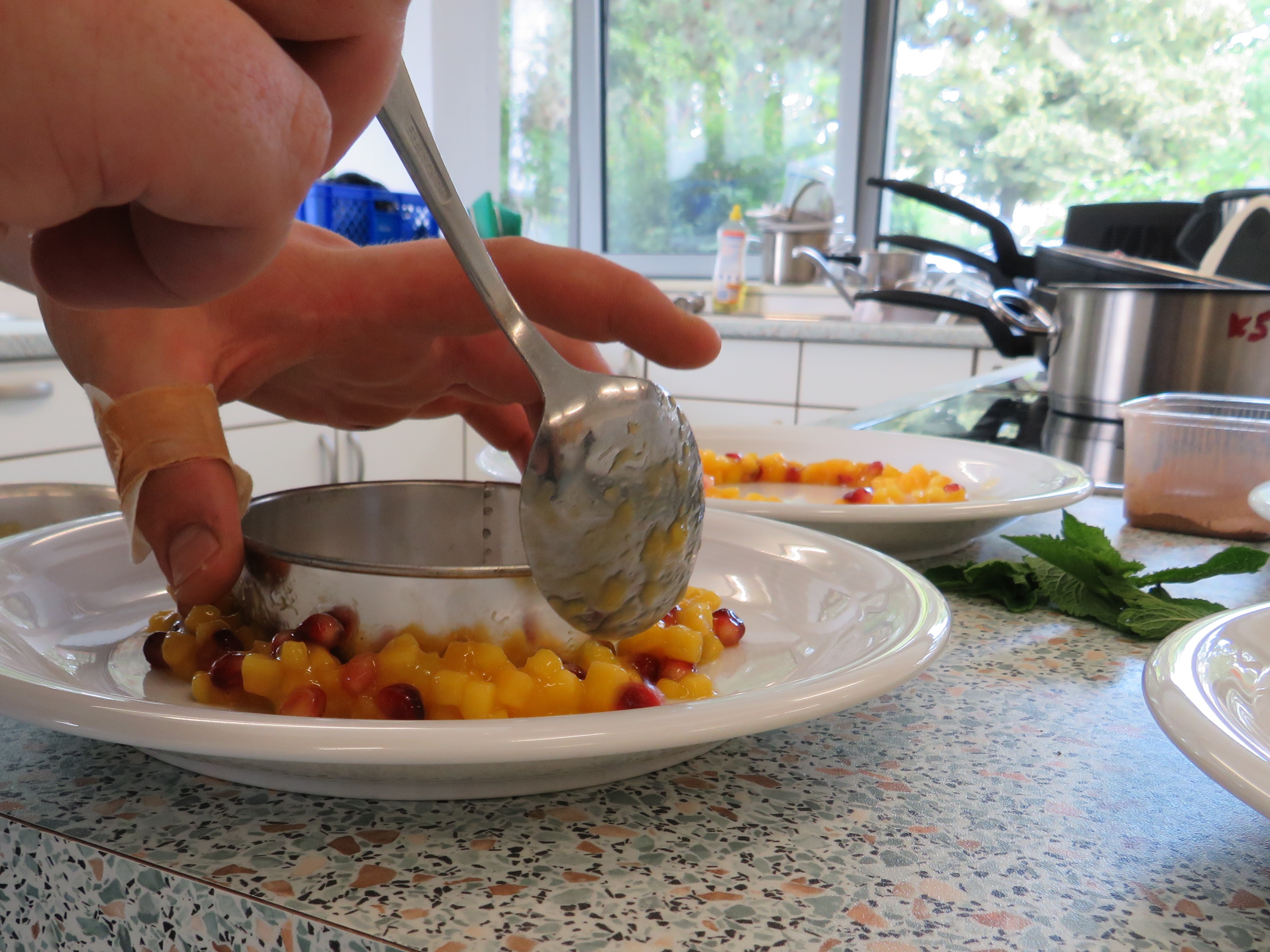mit Hilfe eines Metallrings werden Mango- und Granatapfelstück angerichtet - das Bild wird mit Klick vergrößert