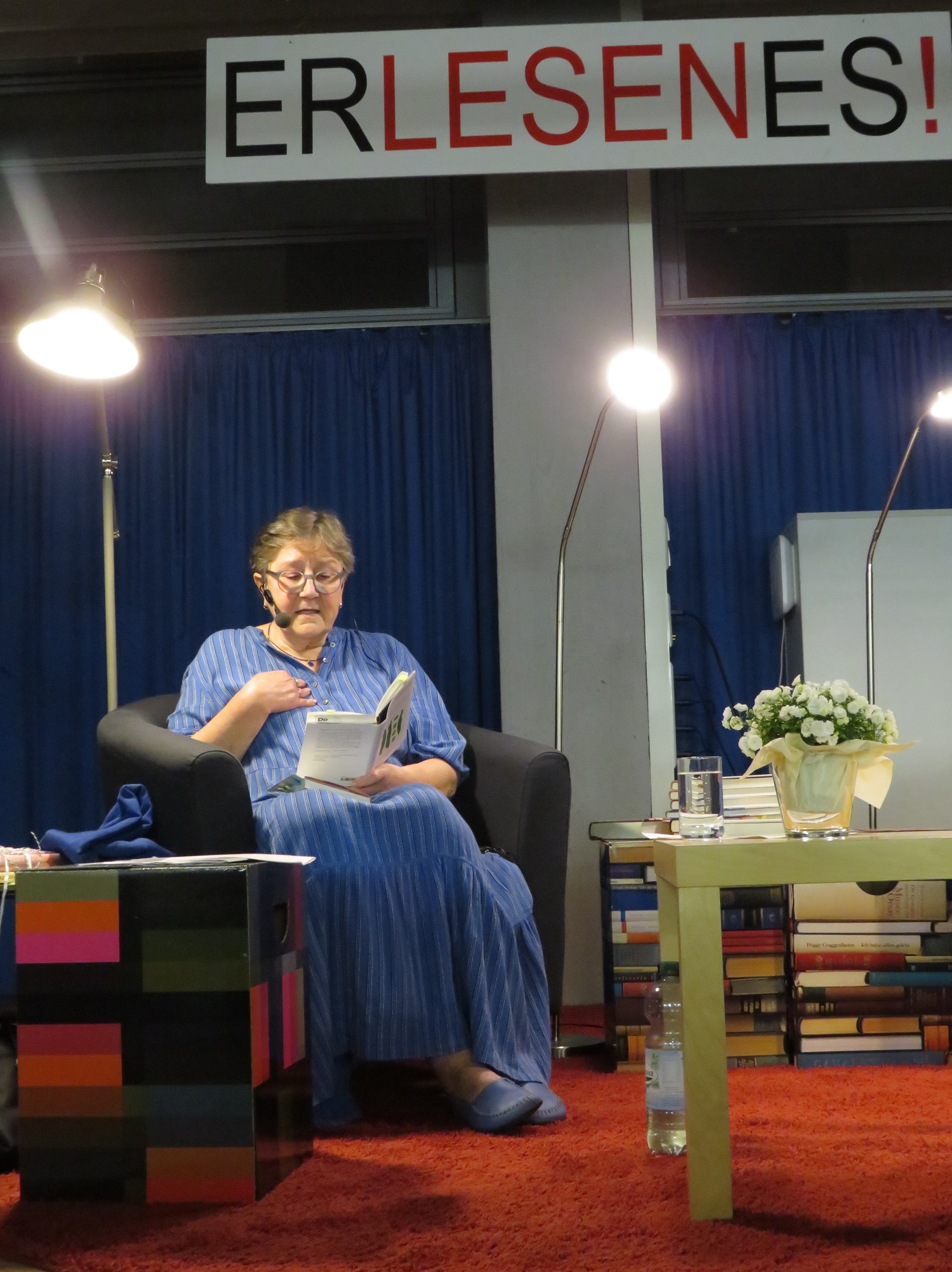  2. Ursula Gmähle liest, in einem Sessel sitzend, aus einem Buch vor - das Bild wird mit Klick vergrößert 