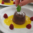 angerichteter Dessertteller: Lavaküchlein auf Mangopüree mit Himbeeren - das Bild wird mit Klick vergrößert
